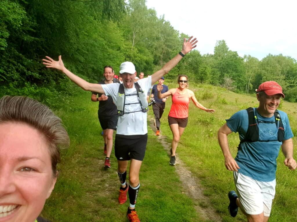 Vrolijke groep runners tijdens een training in de natuur bij Velde; genieten van hardlopen en bootcampen in het groene landschap.