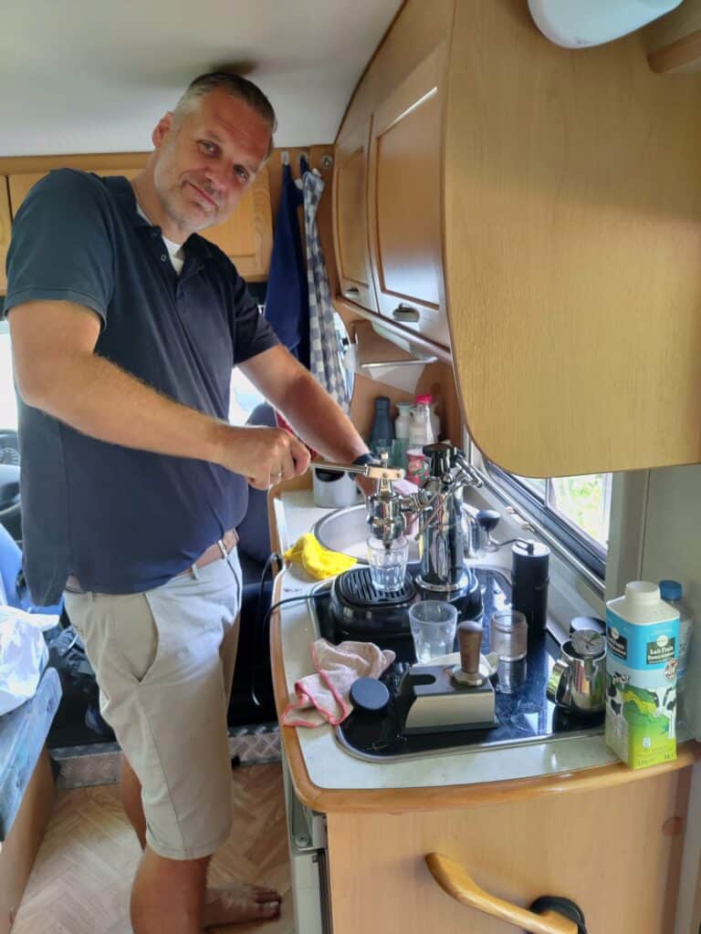 Ontspannen man bereidt zich voor op training in een keuken, met sportartikelen en waterflesjes op het aanrecht.