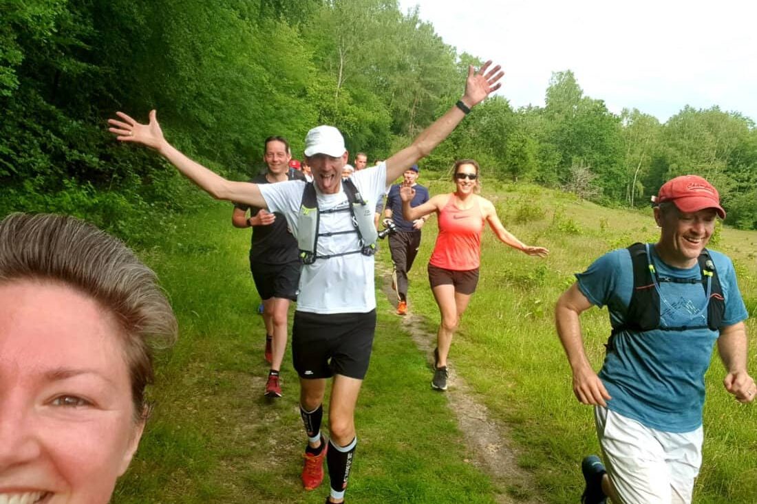 Vrolijke groep runners tijdens een training in de natuur bij Velde; genieten van hardlopen en bootcampen in het groene landschap.